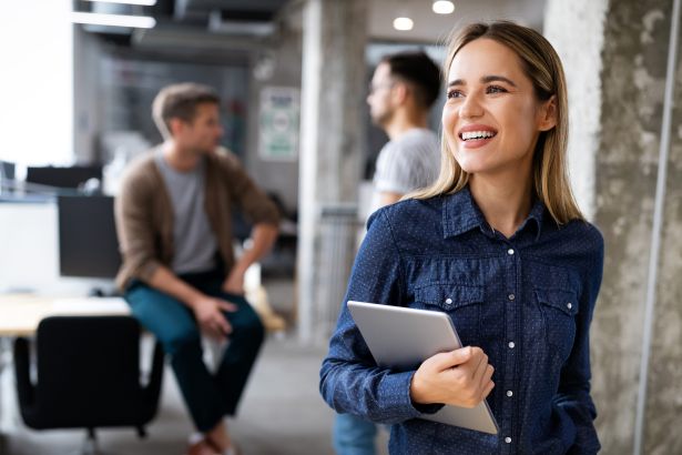 Startup-Büro, Person mit Tablet im Vordergrund, zwei weitere Personen im Hintergrund